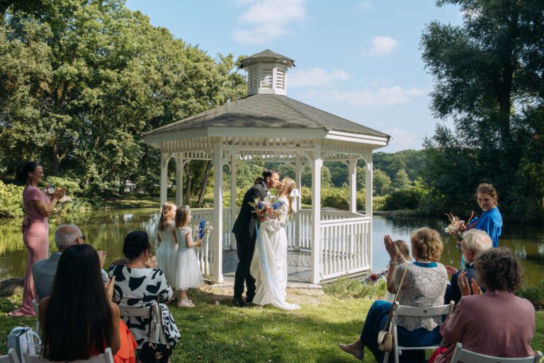 Para młoda całująca się. Wok&oacute;ł goście weselni.