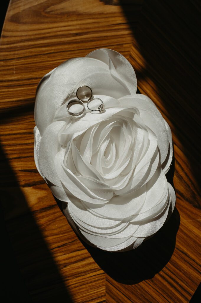 Inne obrączki położone na torebce biały kwiat.