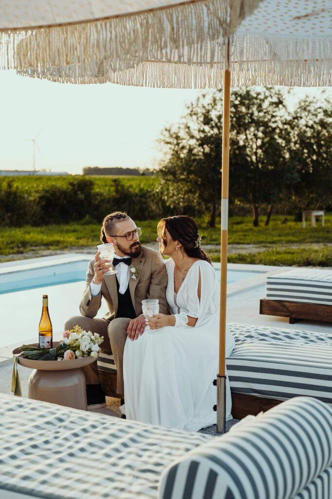 Para młoda sidzi na leżanku nad basenem w Rusborek Slow i pije wino.