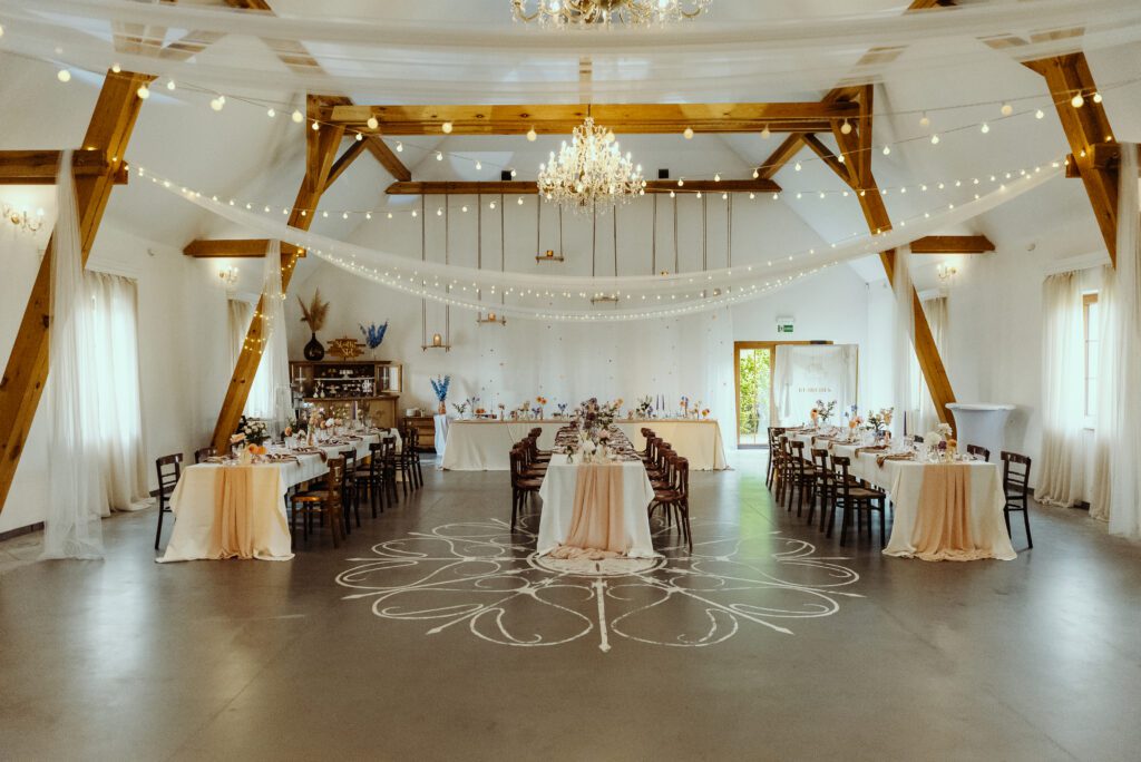300525_0287 rustykalna sala weselna w Rusiborek Dom, podłużne kwadratowe stołu, kolorowe dekoracje, belki pod sufitem