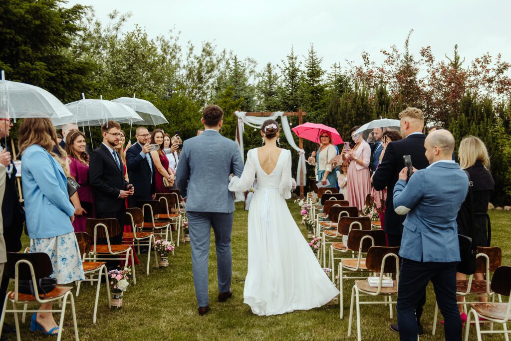 300525_0376 ślub w plenerze w deszczu, niektórzy goście pod parasolami