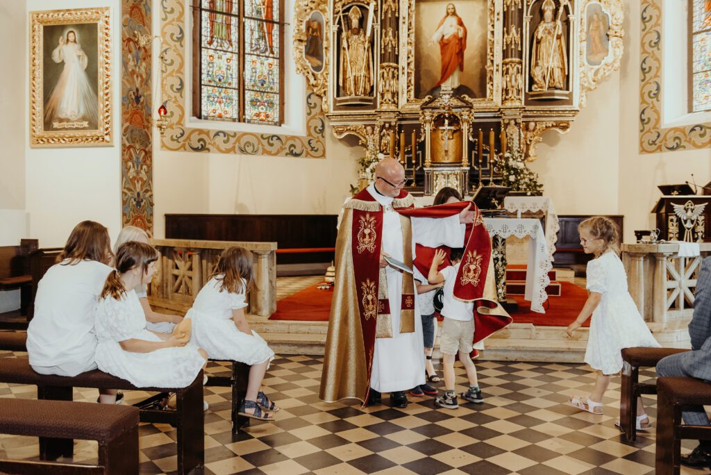 ksiądz z dziećmi podczas chrztu św.