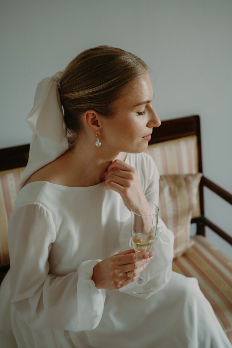 Portret panny młodej siedzącej i pijącej szampana. Chwilla skupienia.