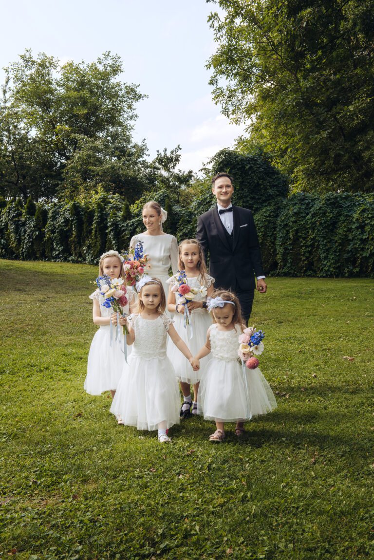 Para młoda idzie do ołtarza w otoczeniu dzieci trzymających kwiaty.