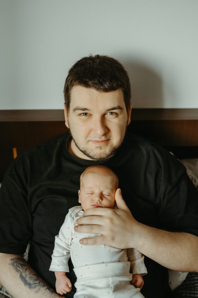 Noworodek leżący na klatce taty. Sesja noworodkowa w bloku.