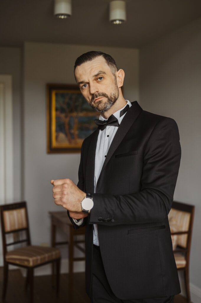 Pan młody zakładający zegarek. Przygotowania ślubnne pana młodego.