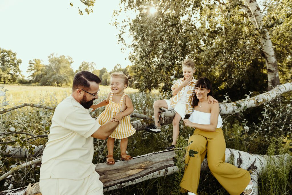 DSC_0954 Rodzinna sesja w plenerze. Rodzinka się bawi. Siedzą na powalonym brzewie. Jest pieknyy letni dzień.